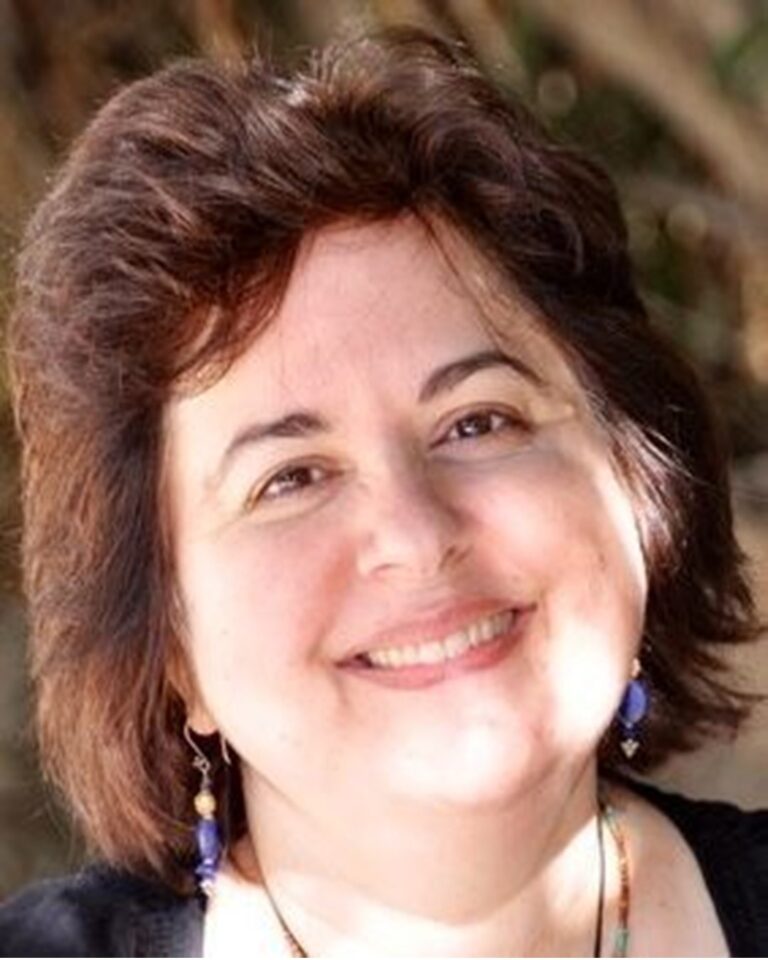 Smiling woman with curly hair and earrings in natural light.
