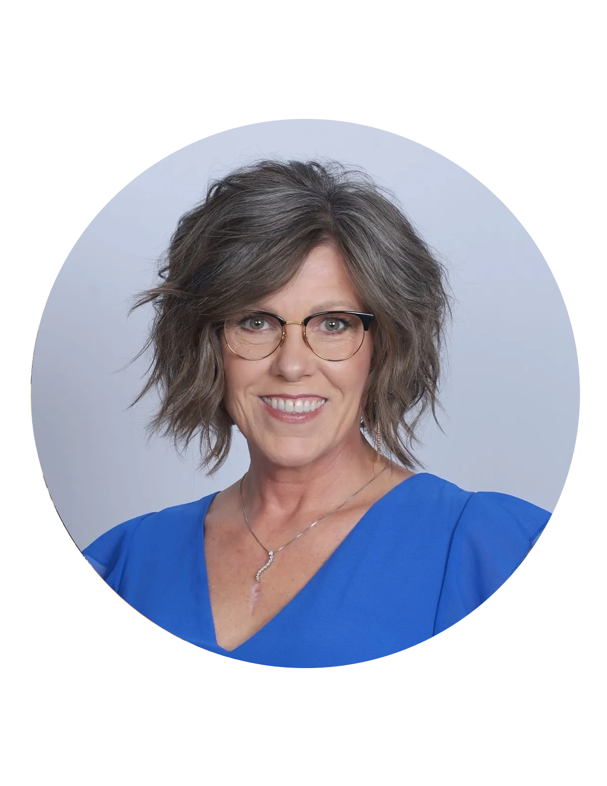 Professional woman with glasses and wavy gray hair in blue blouse.