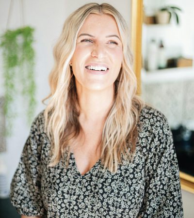 Smiling woman with long blonde hair in a patterned blouse.